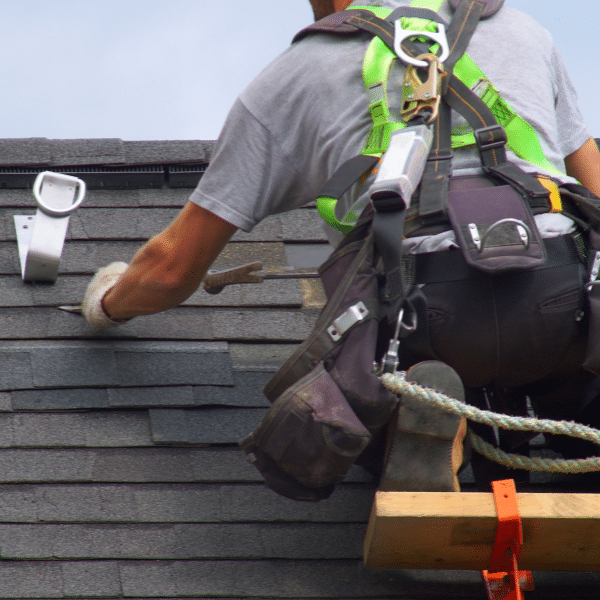 Roofing contractor installing new shingles and gutters together